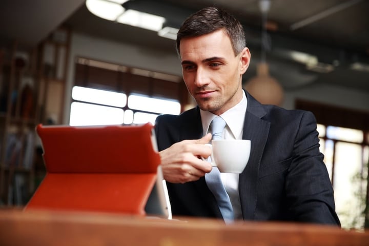 Businessman drinking coffee and reading news in cafe